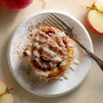 A glazed apple cinnamon roll served on a plate