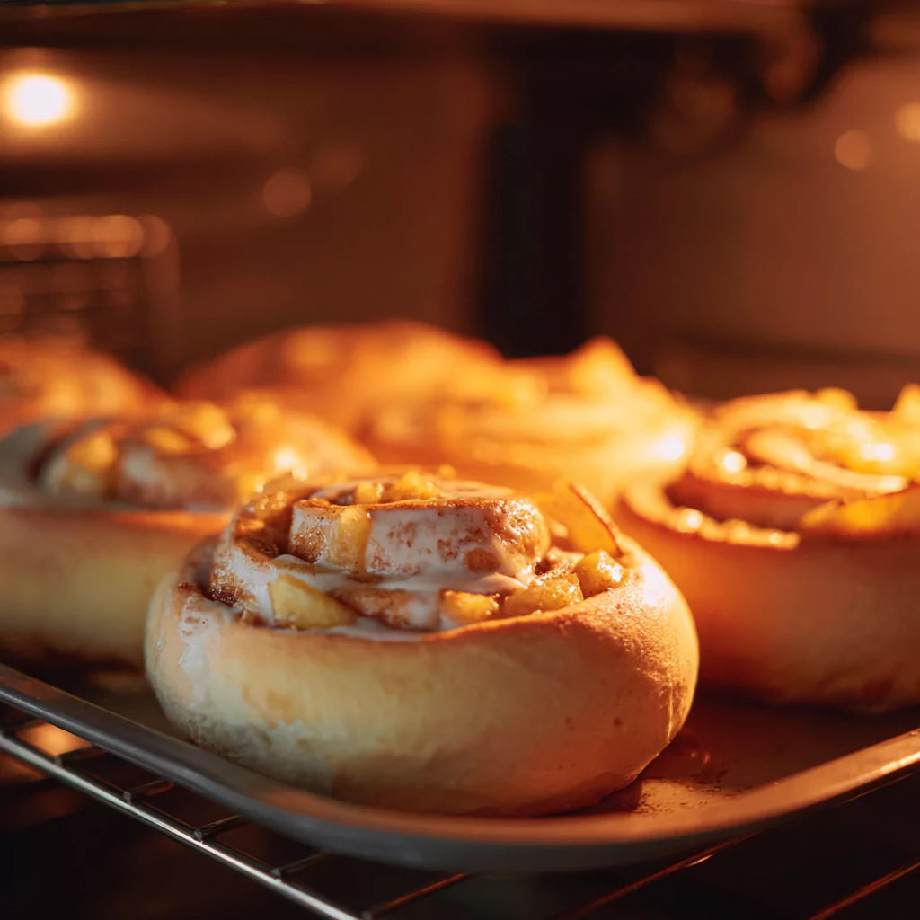 Apple cinnamon rolls rising and baking to golden perfection in oven