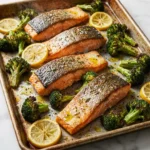 Sheet pan roasted salmon with broccoli and lemon on a serving plate