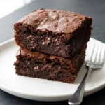 Fudgy pumpkin protein brownies on a plate, garnished with nuts and chocolate drizzle.