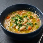 Bowl of hearty white bean soup garnished with herbs and spices